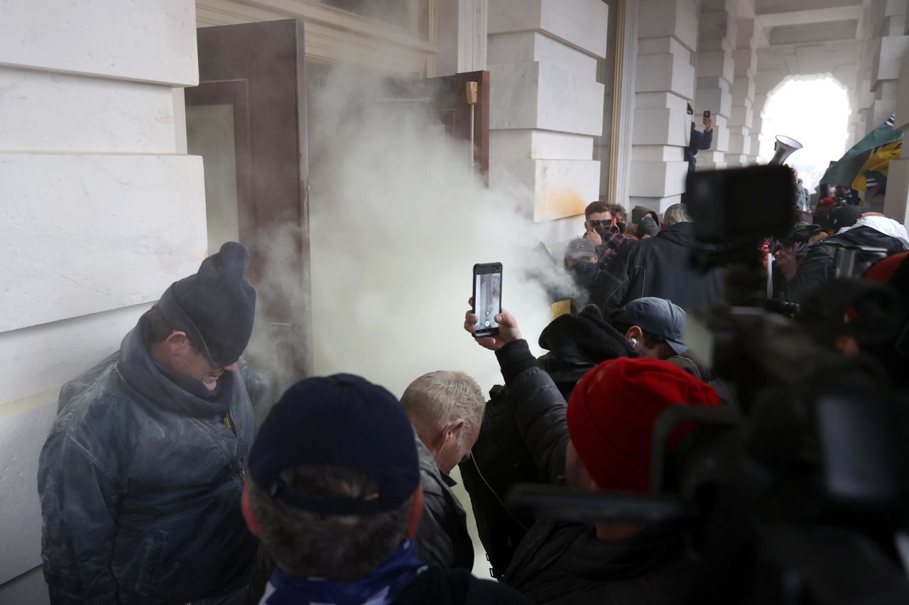Tear gas is deployed as rioters gather outside the Capitol.