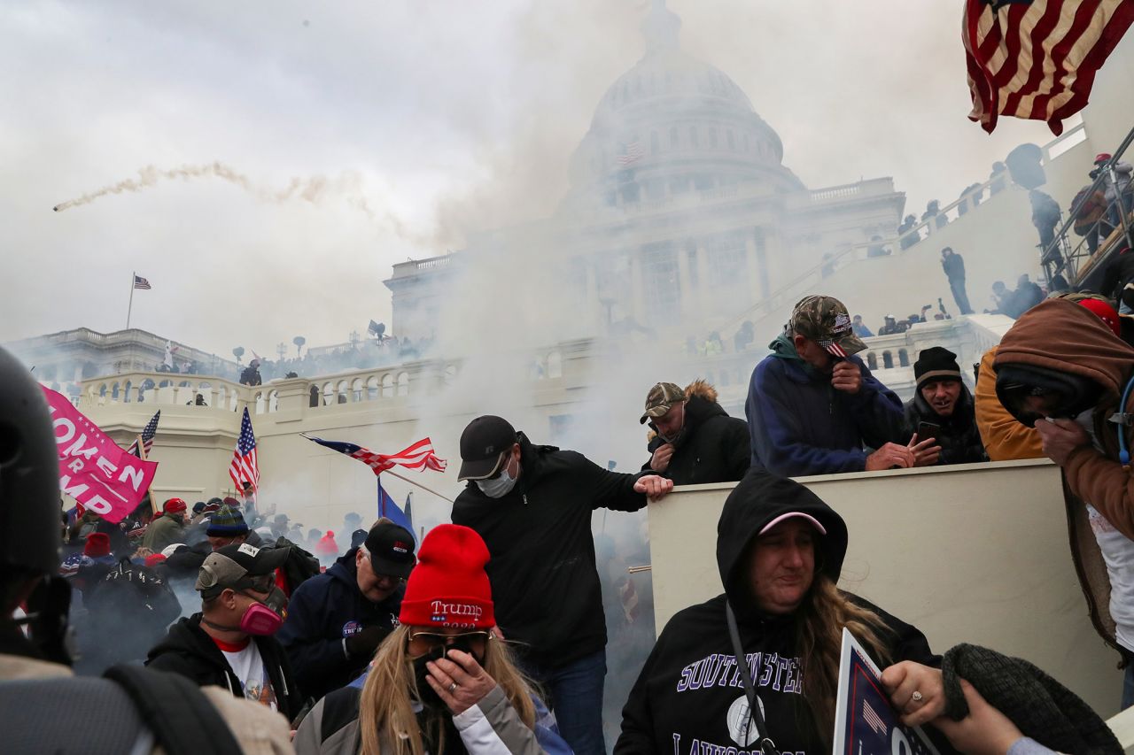 Trump supporters cover their faces after tear gas was fired in front of the Capitol.