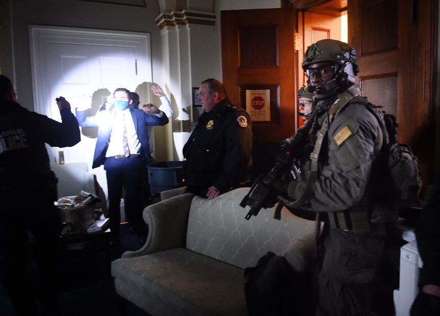 Congressional staffers hold up their hands while Capitol Police SWAT teams secure the US Capitol.