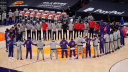 Members of the Phoenix Suns and the Toronto Raptors form a circle during the US National Anthem prior to an NBA game Wednesday