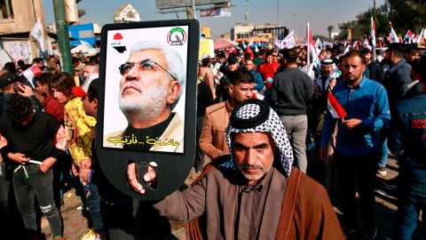 A supporter of Abu Mahdi al-Muhandis, deputy commander of the Popular Mobilization Forces, holds a photo of him during a protest in Tahrir Square, Baghdad, Iraq, Sunday, Jan. 3, 2021.