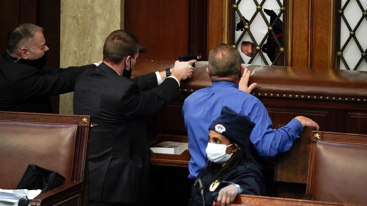 Police draw guns as rioters try to break into the House Chamber during the January 6 siege.