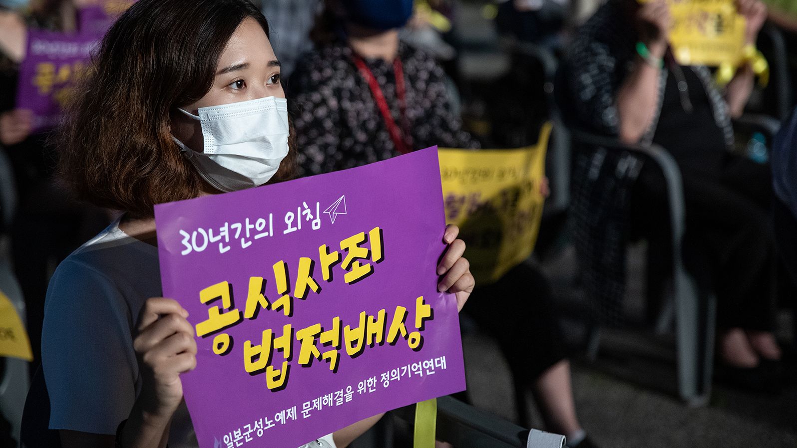 A woman holds a sign demanding a formal apology and compensation from Japan, at a rally marking the 2020 International Memorial Day for Comfort Women in Seoul, South Korea. 