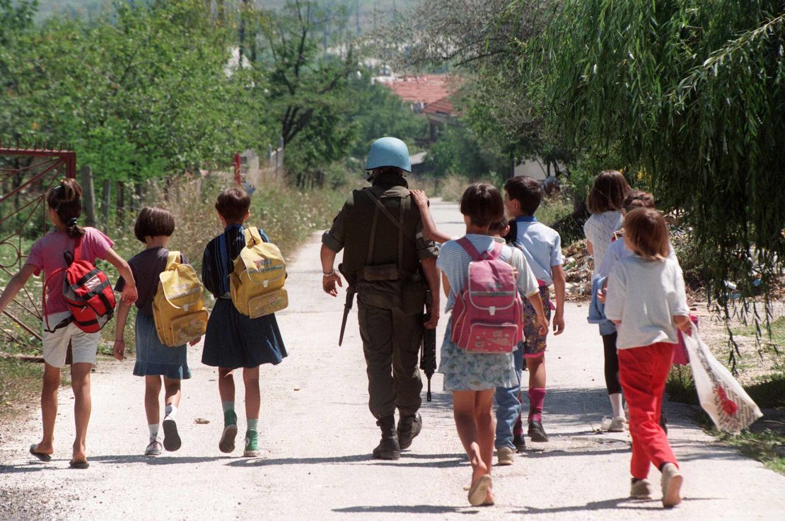 A United Nations Protection Force French soldier escorts a group of children after they left their school in a Sarajevo neighborhood a few hundred meters from the front line on August 14, 1993.