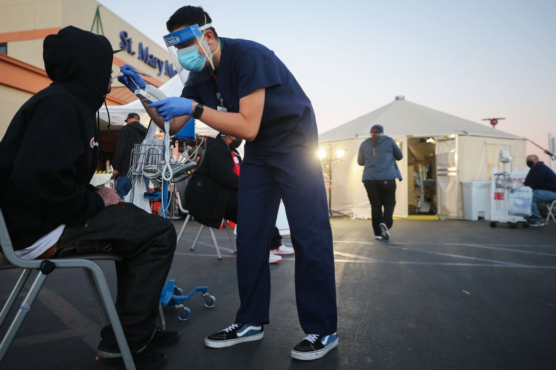 A California National Guard medic checks an incoming patient's vital signs in front of triage tents outside St. Mary Medical Center.