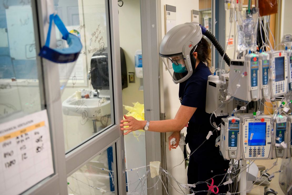 A nurse wearing personal protective equipment (PPE), including a personal air purifying respirator (PAPR), closes a door to a patient's room in a Covid-19 intensive care unit at Martin Luther King Jr. (MLK) Community Hospital on January 6, in the Willowbrook neighborhood of Los Angeles.
