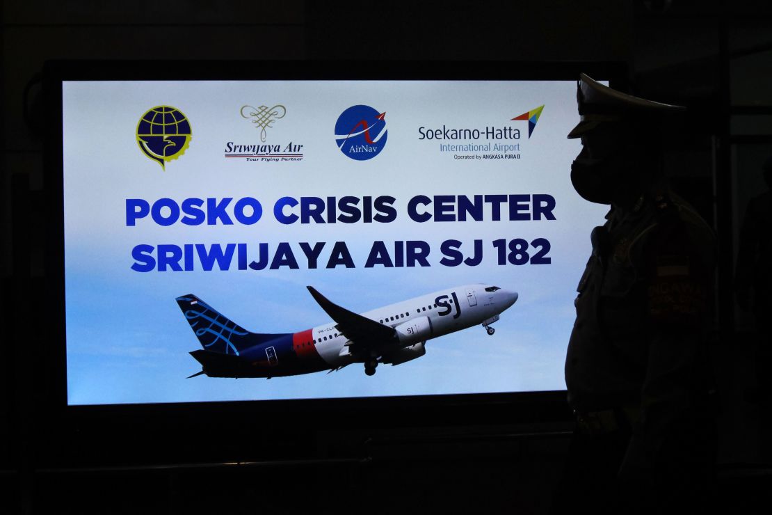 A security personnel stands in front of a sign for a crisis centre for Sriwijaya Air flight SJY182 at the Soekarno-Hatta international airport in Tangerang near Jakarta on January 9, 2021.