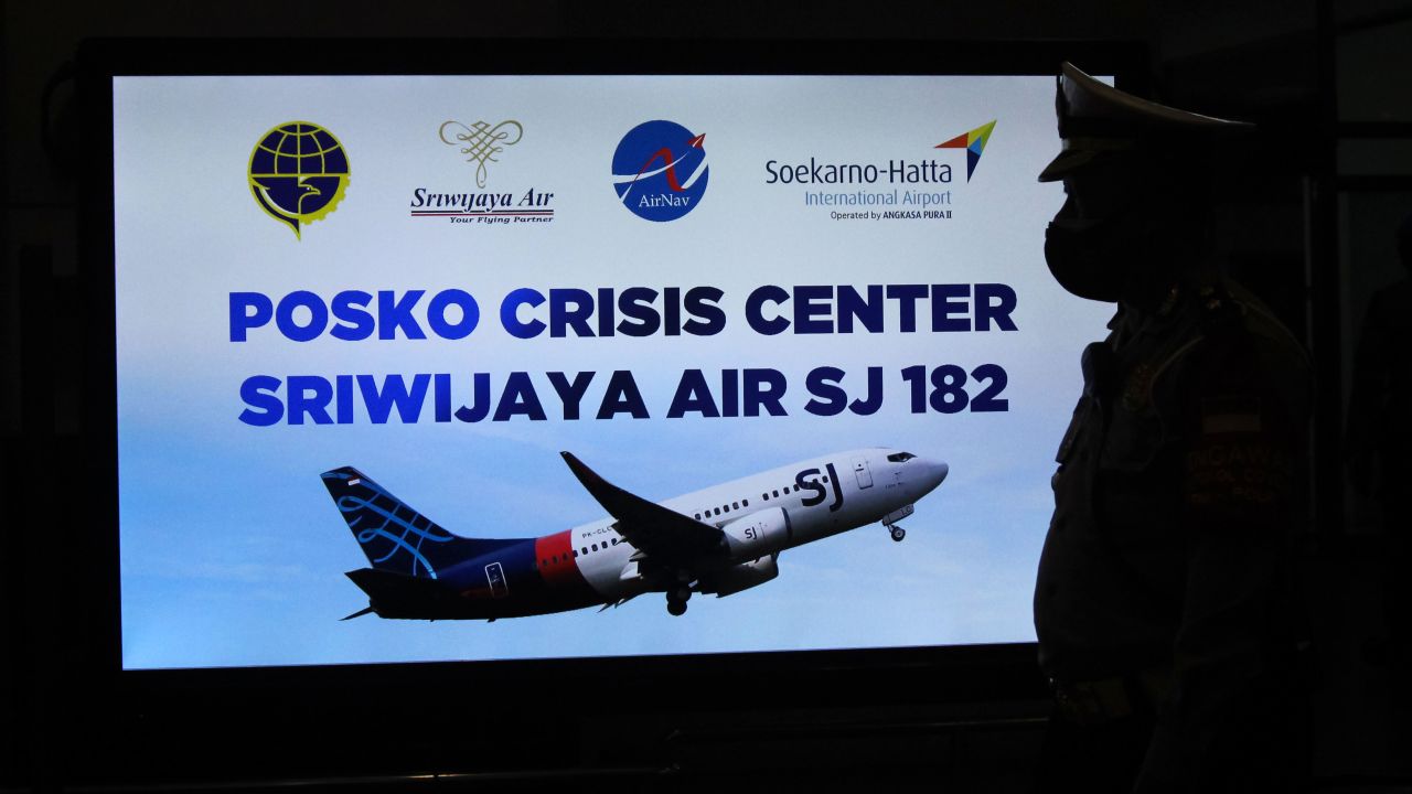 A security personnel stands in front of a sign for a crisis centre for Sriwijaya Air flight SJY182 at the Soekarno-Hatta international airport in Tangerang near Jakarta on January 9, 2021.
