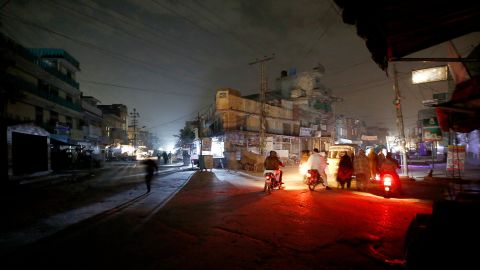 People are silhouetted on vehicles headlights on a dark street during widespread power outages in Rawalpindi, Pakistan, Sunday, Jan. 10, 2021. Pakistan's national power grid experienced a major breakdown late night on Saturday, leaving millions of people in darkness, local media reported. (AP Photo/Anjum Naveed)