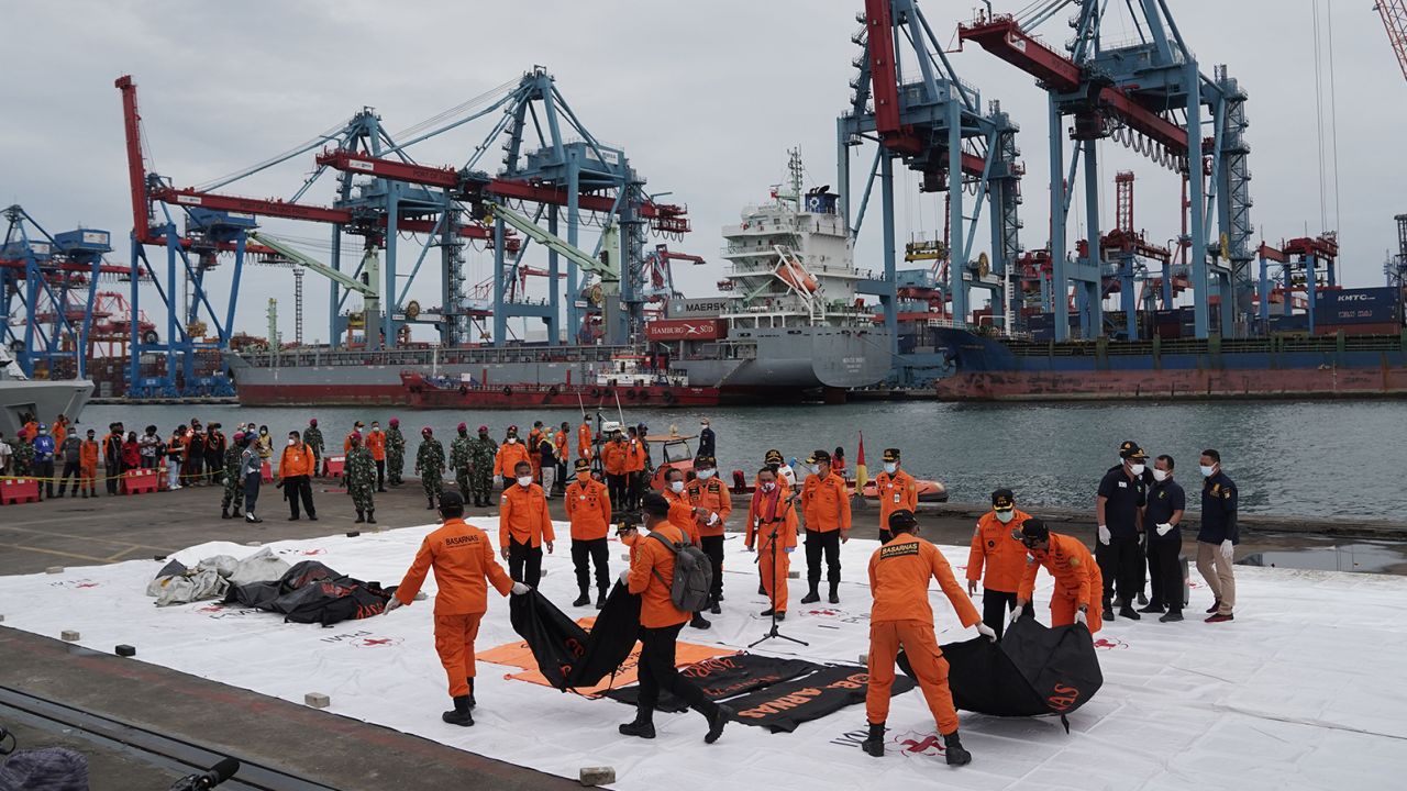 Search and rescue team members carry bags containing remains of victims recovered from the Sriwijaya Air SJ 182 crash site on the dockside at Tanjung Priok Port in Jakarta, Indonesia, on Sunday.