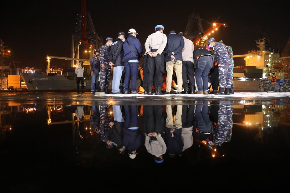 Officers from the National Search and Rescue Agency of Indonesia check a fragment of the plane at the Tanjung Priok port.