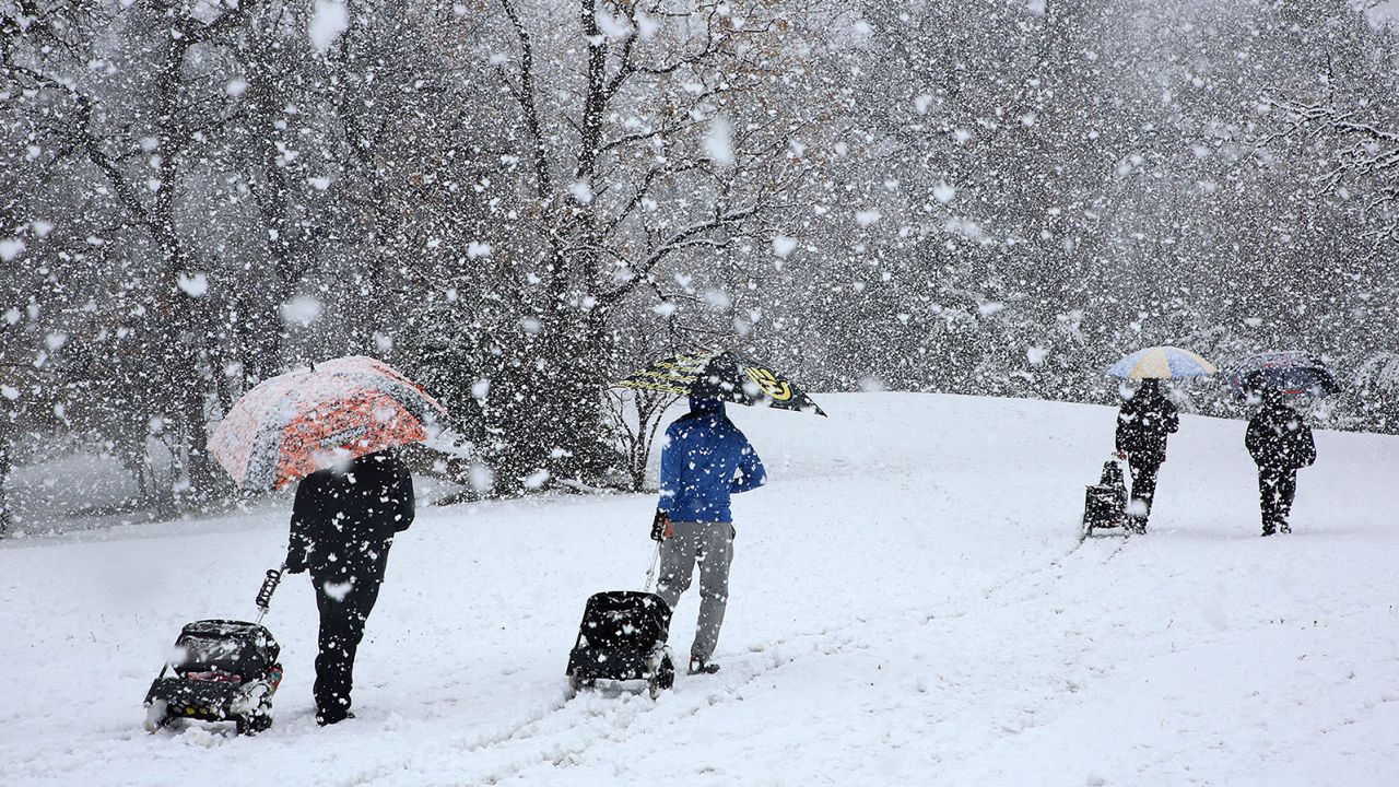 Disc golfers make their way through the snow that dropped at least five inches at their tournament in Cameron Park in Waco, Texas, on Sunday.