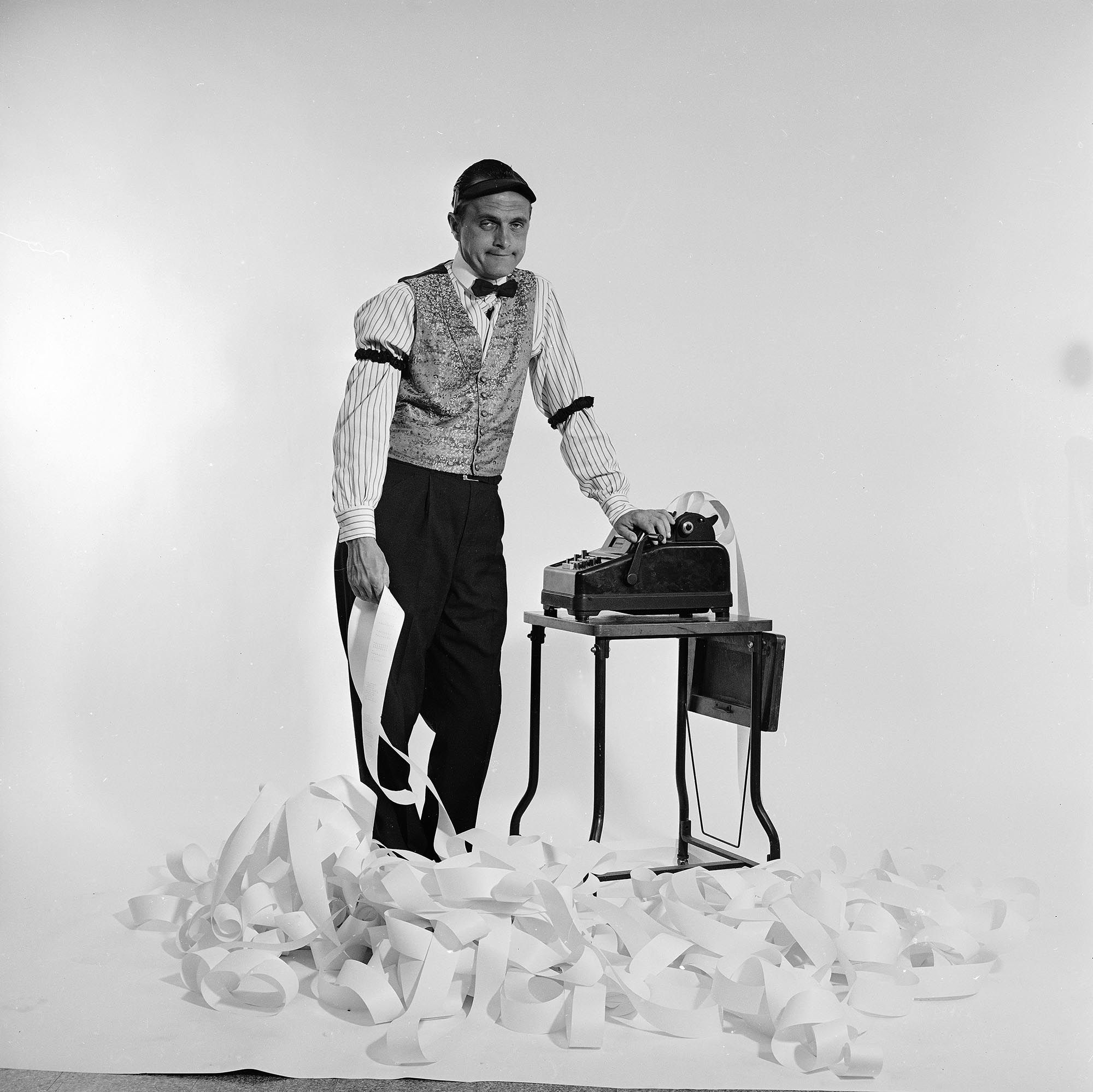 Newhart poses as an addled accountant at an adding machine for a promotional photo of 'The Bob Newhart Show.'