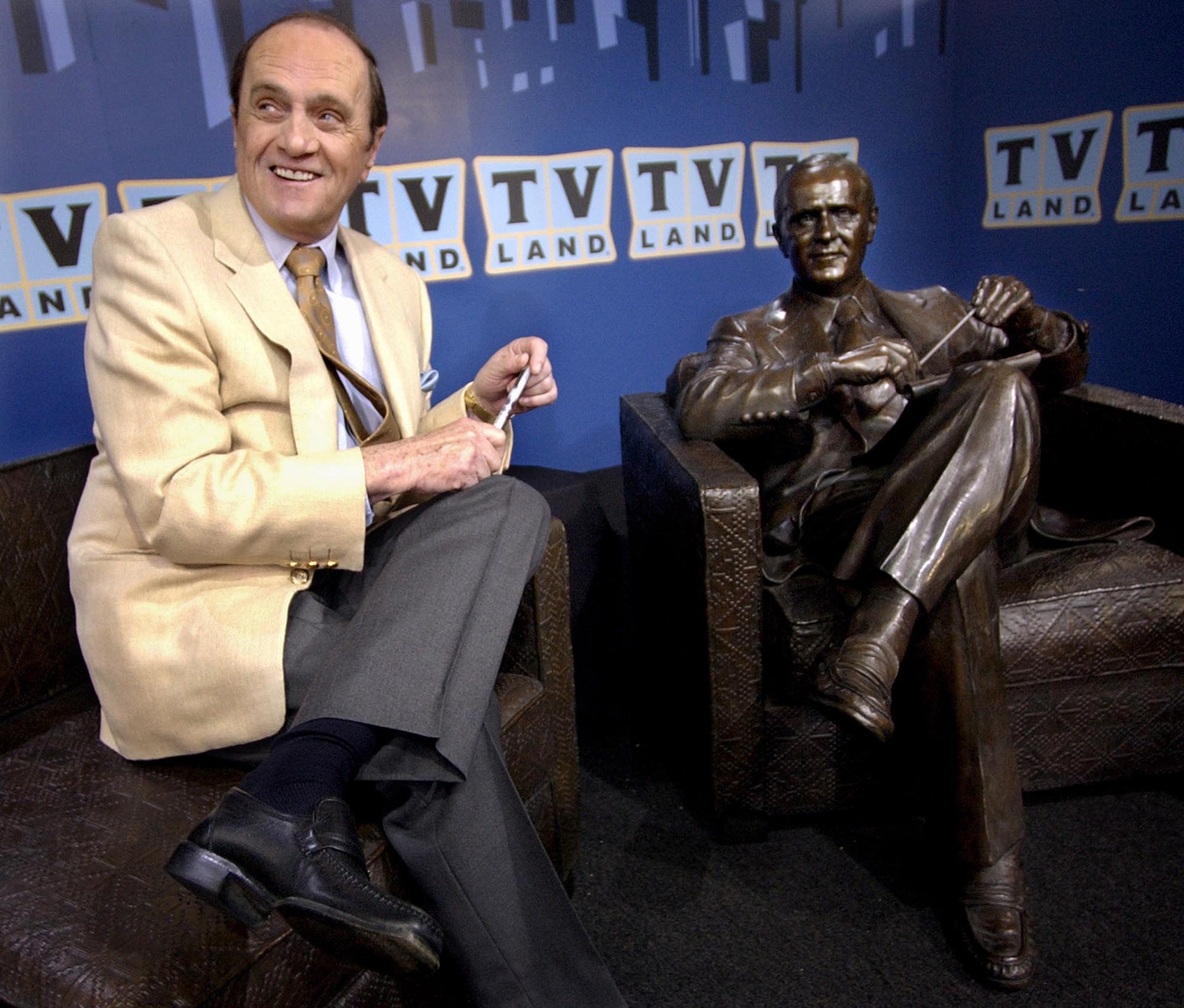 Newhart sits with a bronze likeness of Bob Hartley at its unveiling in Chicago in 2004.