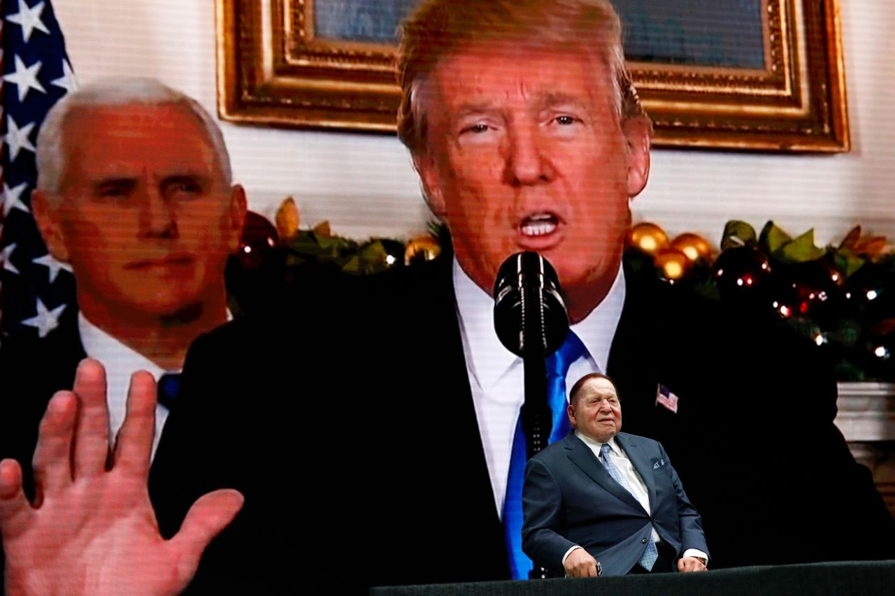 Adelson sits on stage as a video screen depicts Trump and Vice President Mike Pence at the Israeli American Council National Summit in 2019.