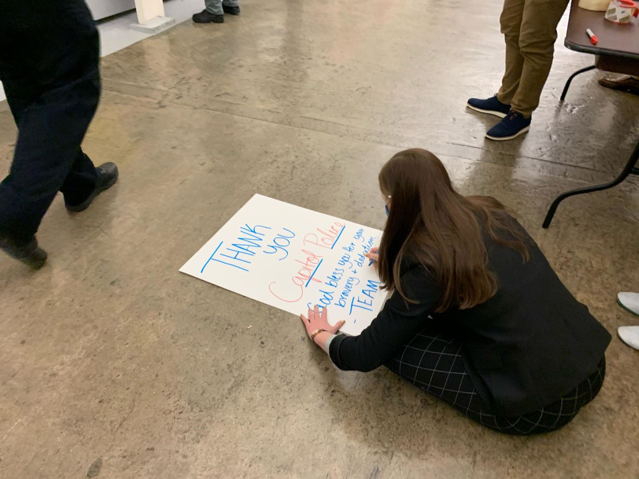 A woman sits on the floor of a House tunnel as she writes supportive messages to the US Capitol Police from her and her team.