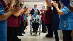 COVENTRY, ENGLAND - DECEMBER 08: Margaret Keenan, 90, is applauded by staff as she returns to her ward after becoming the first person in the United Kingdom to receive the Pfizer/BioNtech covid-19 vaccine at University Hospital at the start of the largest ever immunisation programme in the UK's history on December 8, 2020 in Coventry, United Kingdom. More than 50 hospitals across England were designated as covid-19 vaccine hubs, the first stage of what will be a lengthy vaccination campaign. NHS staff, over-80s, and care home residents will be among the first to receive the Pfizer/BioNTech vaccine, which recently received emergency approval from the country's health authorities. (Photo by Jacob King - Pool / Getty Images)