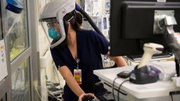 A nurse wearing personal protective equipment (PPE) including a personal air purifying respirator (PAPR) looks through a door into a patients room in a Covid-19 intensive care unit (ICU) at Martin Luther King Jr. (MLK) Community Hospital on January 6, 2021 in the Willowbrook neighborhood of Los Angeles, California. - Deep within a South Los Angeles hospital, a row of elderly Hispanic men in induced comas lay hooked up to ventilators, while nurses clad in spacesuit-looking respirators checked their bleeping monitors in the eerie silence. The intensive care unit in one of the city's poorest districts is well accustomed to death, but with Los Angeles now at the heart of the United States' Covid pandemic, medics say they have never seen anything on this scale. (Photo by Patrick Fallon/AFP/Getty Images)