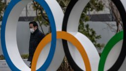 TOKYO, JAPAN - JANUARY 12: A man wearing a face mask walks past the Olympic Rings on January 12, 2021 in Tokyo, Japan. Recent surveys by Kyodo News and Tokyo Broadcasting System found that over 80 percent of people in Japan who were questioned believe the Tokyo Olympics should be cancelled or postponed or that the Olympics will not take place. Tokyo remains in a second state of emergency amid a third wave of Covid-19 coronavirus that has seen infection rates climb to unprecedented levels. (Photo by Carl Court/Getty Images)