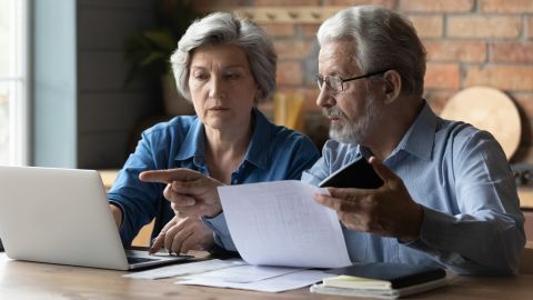 underscored older couple on laptop with papers