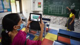 A teacher records a video while her colleague conducts an online class for their students in New Delhi on September 22.