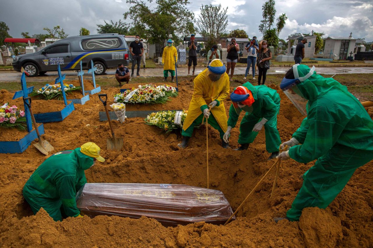 Relatives look on as gravediggers bury a Covid-19 victim at the Nossa Senhora Aparecida cemetery on Wednesday, January 13, in Manaus, Brazil. 