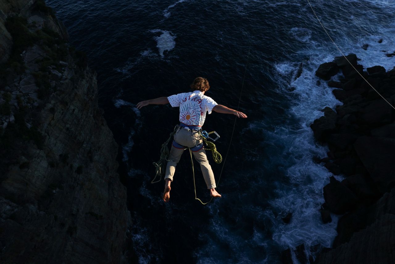 A person leaps from a cliff edge while rope jumping near Currarong, Australia, on Saturday, January 9. 