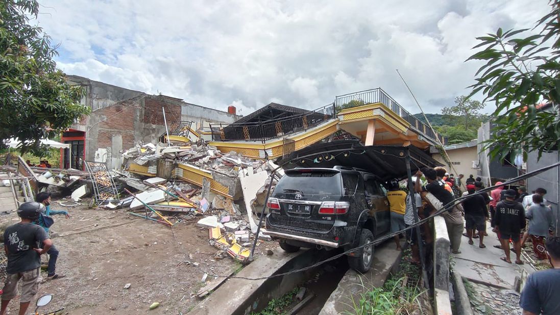 People work at the site of a collapsed building in Mamuju.