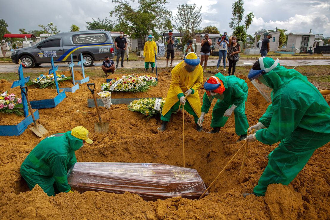Gravediggers bury a Covid-19 victim while surrounded by relatives at the Nossa Senhora Aparecida cemetery in Manaus on January 13, 2021.