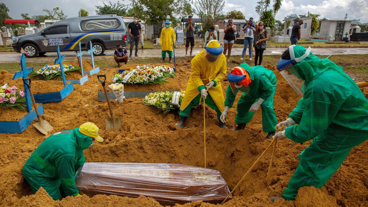 Gravediggers bury a Covid-19 victim while surrounded by relatives at the Nossa Senhora Aparecida cemetery in Manaus on January 13, 2021.