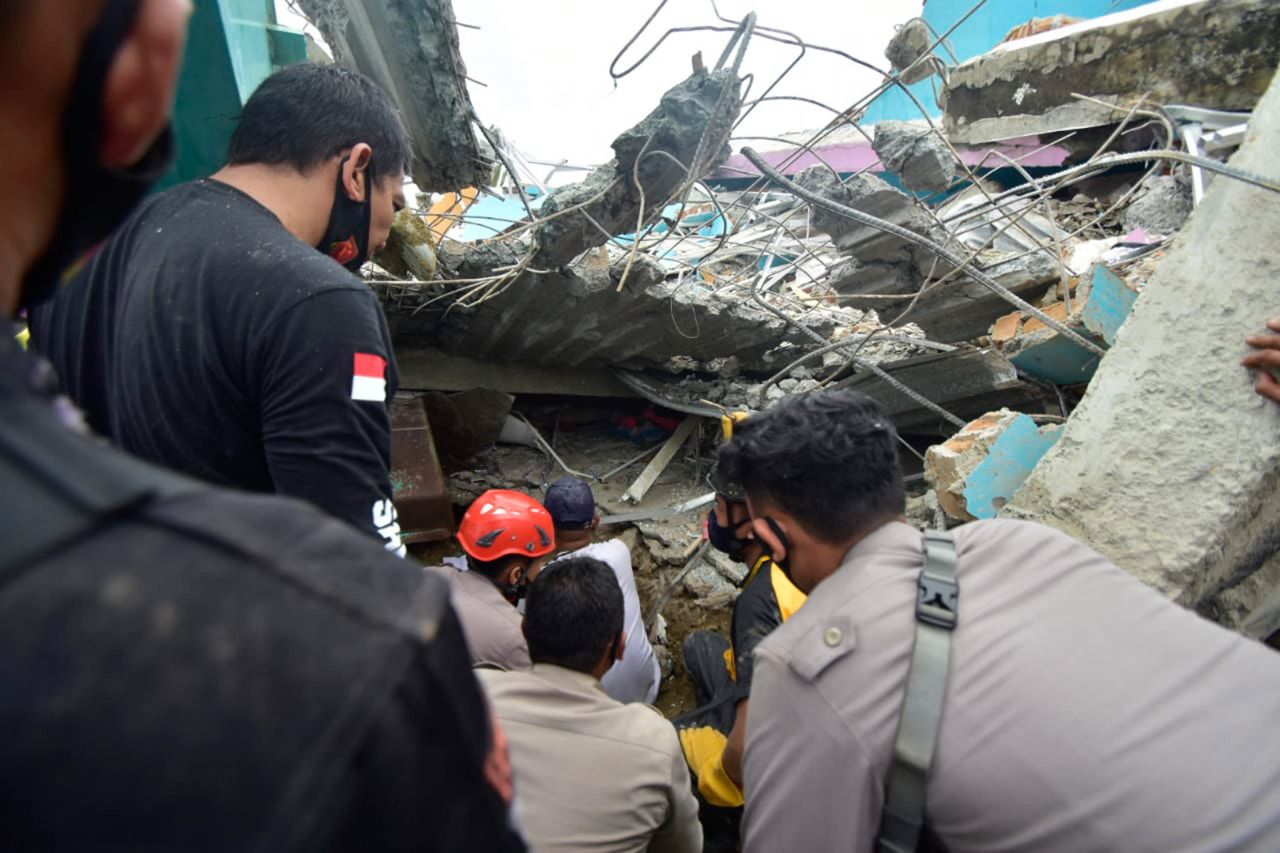 Emergency crews search for survivors among the ruin of a building in Mamuju.