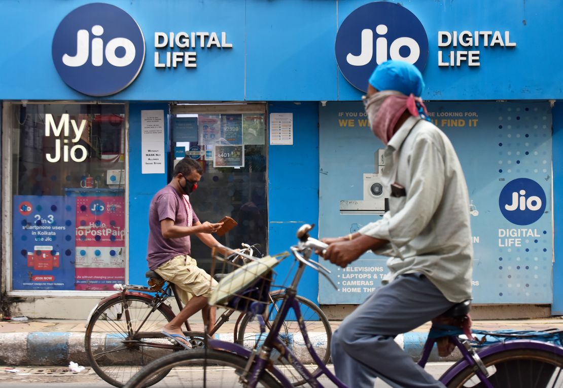 People on bicycle passes by a Jio store in Kolkata, India on July 13, 2020. 