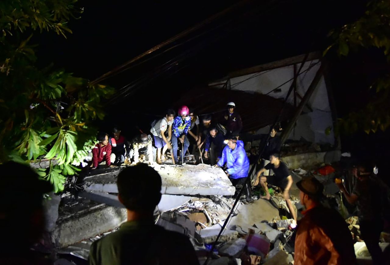Members of emergency services search for survivors at a collapsed building site in Mamuju.