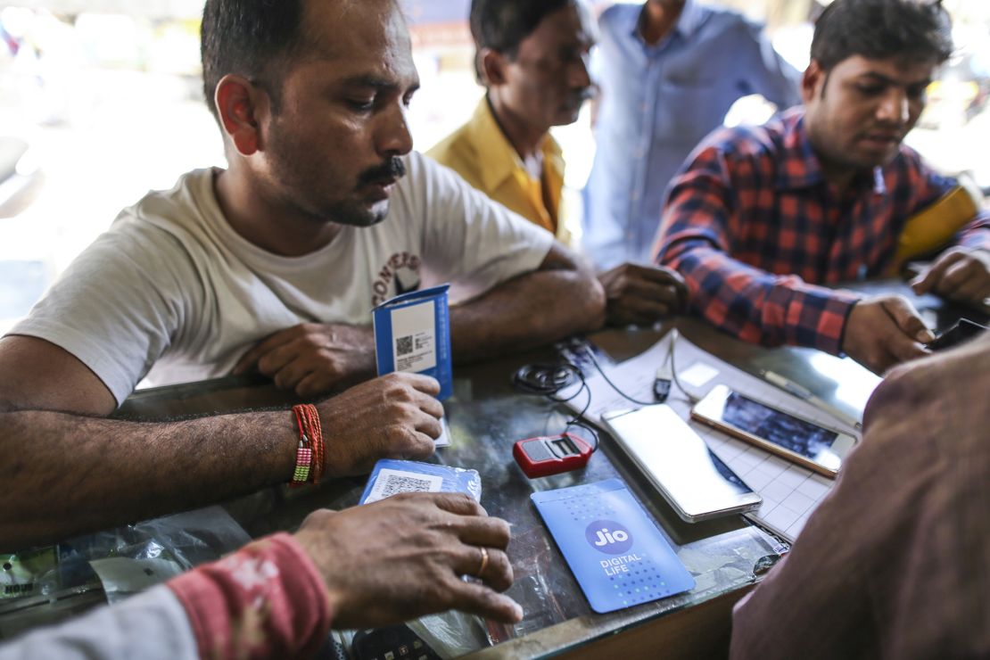 A customer holds a SIM card packet while waiting to connect his mobile phone to the carrier Reliance Jio, the mobile network of Reliance Industries, at a store in Mumbai, India, on Oct. 24, 2016.