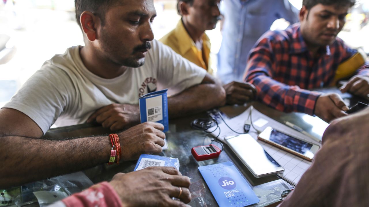 A customer holds a SIM card packet while waiting to connect his mobile phone to the carrier Reliance Jio, the mobile network of Reliance Industries, at a store in Mumbai, India, on Oct. 24, 2016. 