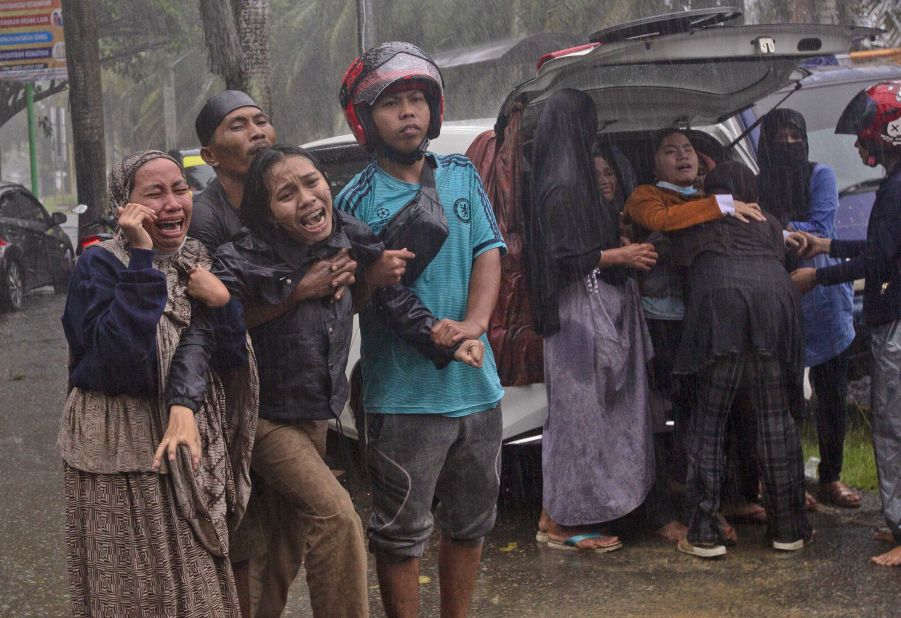 People react as the body of a relative is retrieved from an earthquake-damaged building in Mamuju.