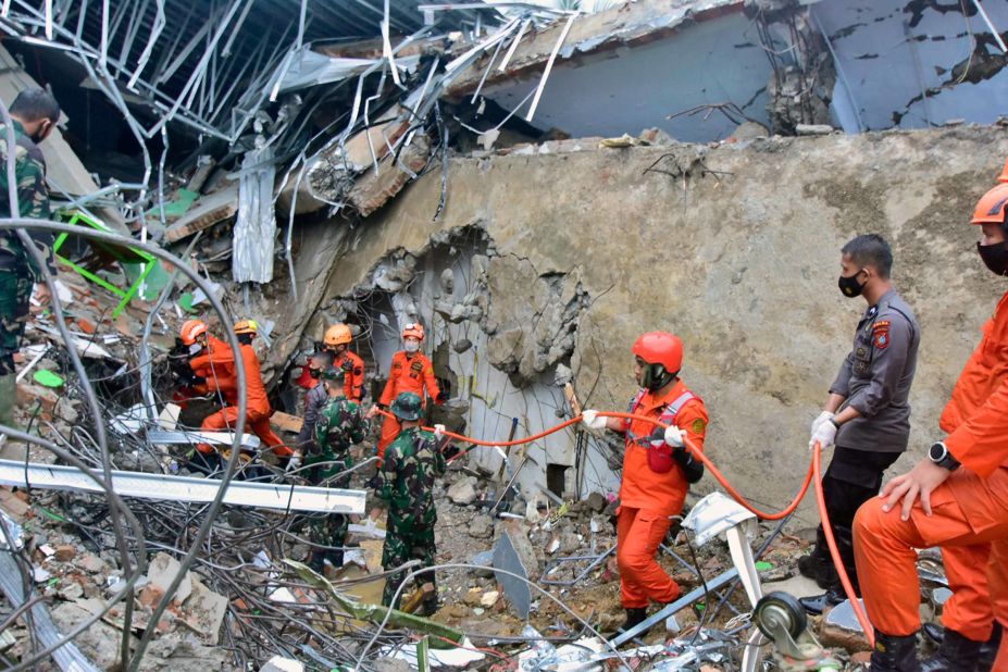 Emergency teams search for survivors amid the debris of a building.