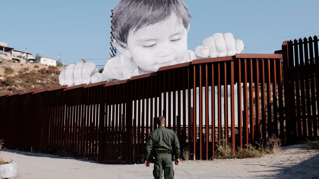 A US Border Patrol officer stands near artwork installed on the Mexican side of the border near Tecate, California.