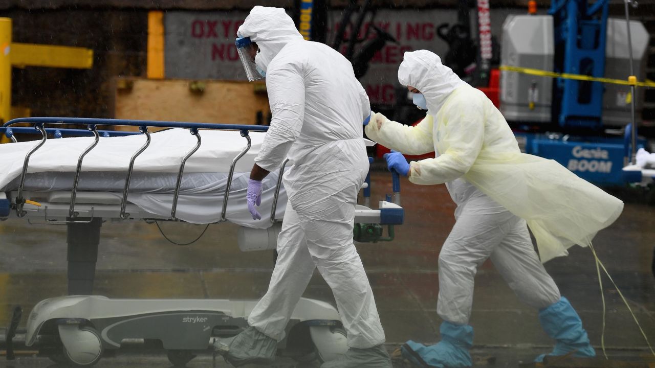 Medical personnel move a deceased patient to a refrigerated truck serving as make shift morgues at Brooklyn Hospital Center on April 9, 2020 in New York City.