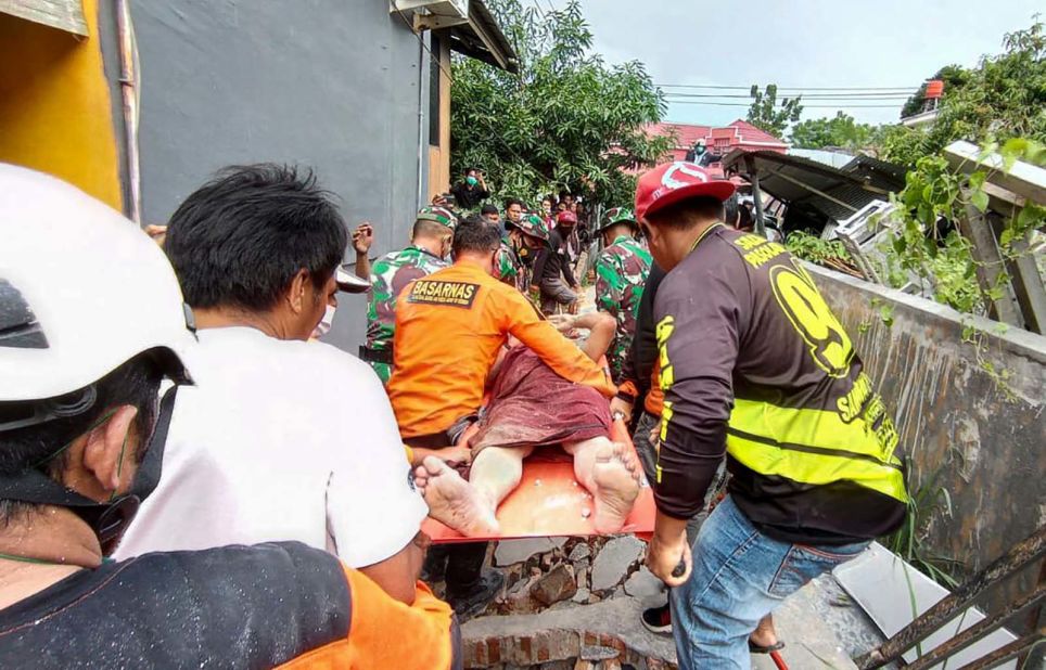 A survivor is carried away from the scene of a destroyed building.