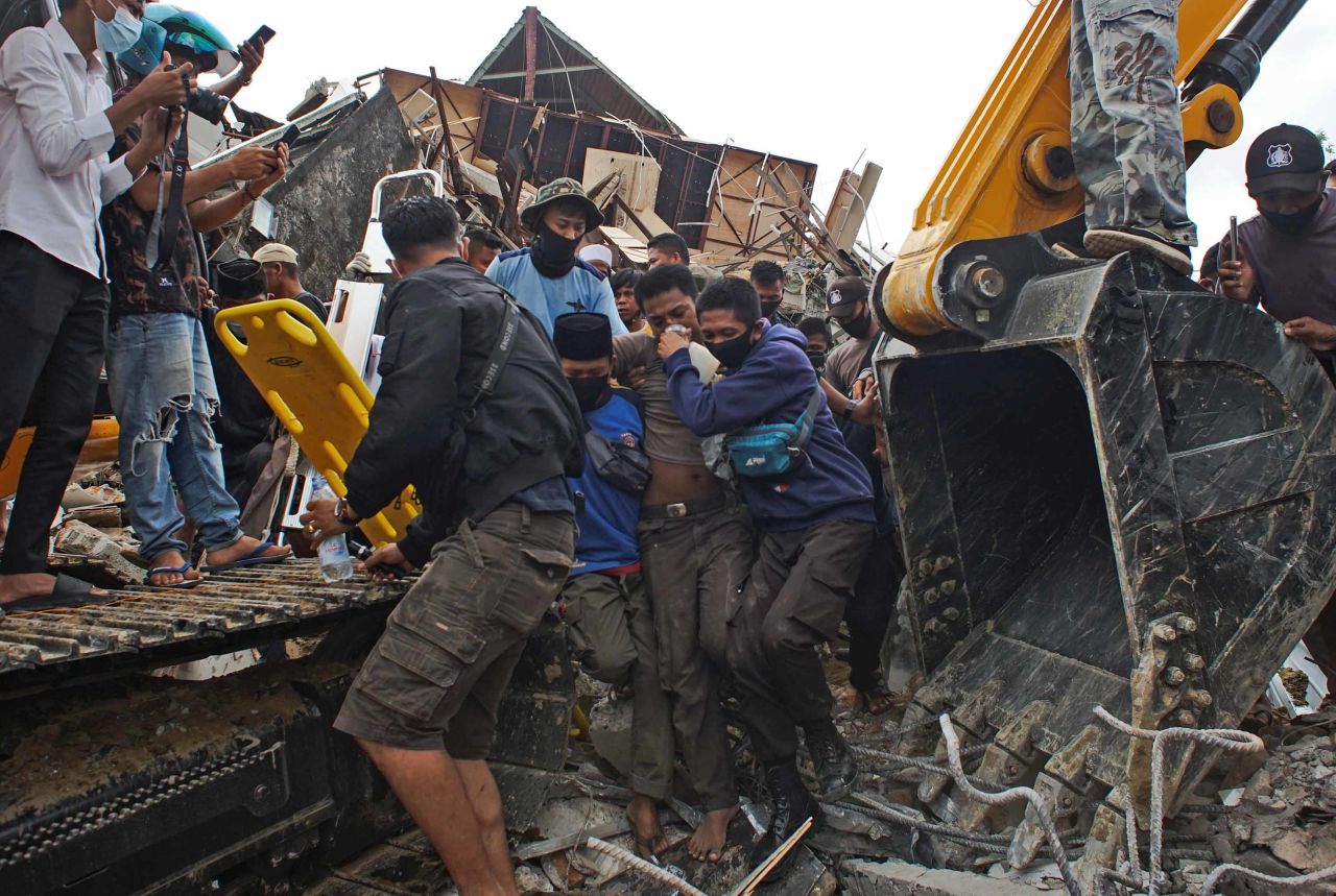 Rescuers assist an earthquake survivor who was pulled from a collapsed government building in Mamuju on Friday, January 15.