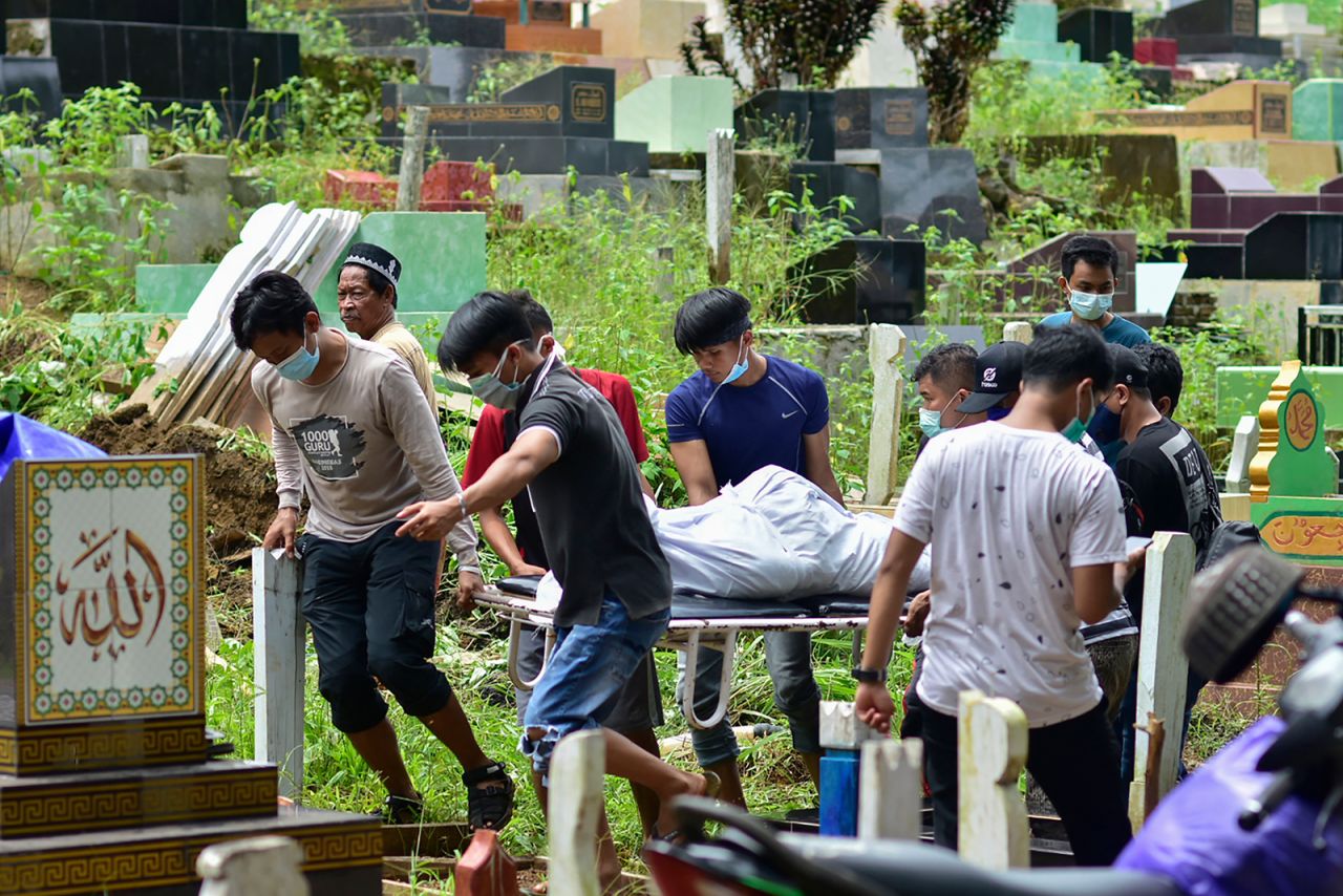 Relatives carry the shrouded body of an earthquake victim for burial at a cemetery in Mamuju.