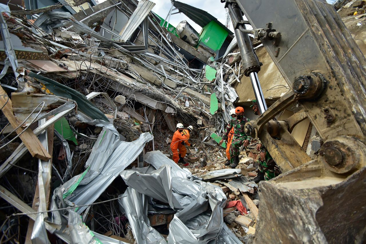 Rescuers search for survivors at the site of a collapsed building in Mamuju.