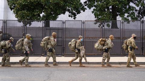 National Guard troops march by security fencing near the US Capitol on January 16, 2021, in Washington, DC.
