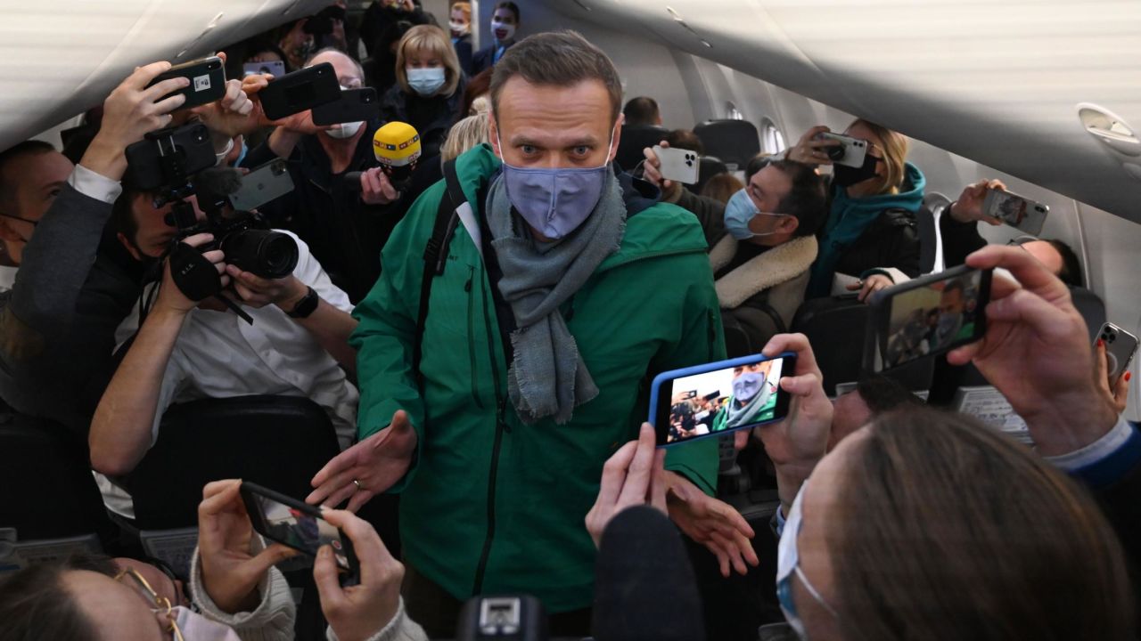 Passengers and journalists take photos of Alexey Navalny as he takes his seat on the flight Sunday.
