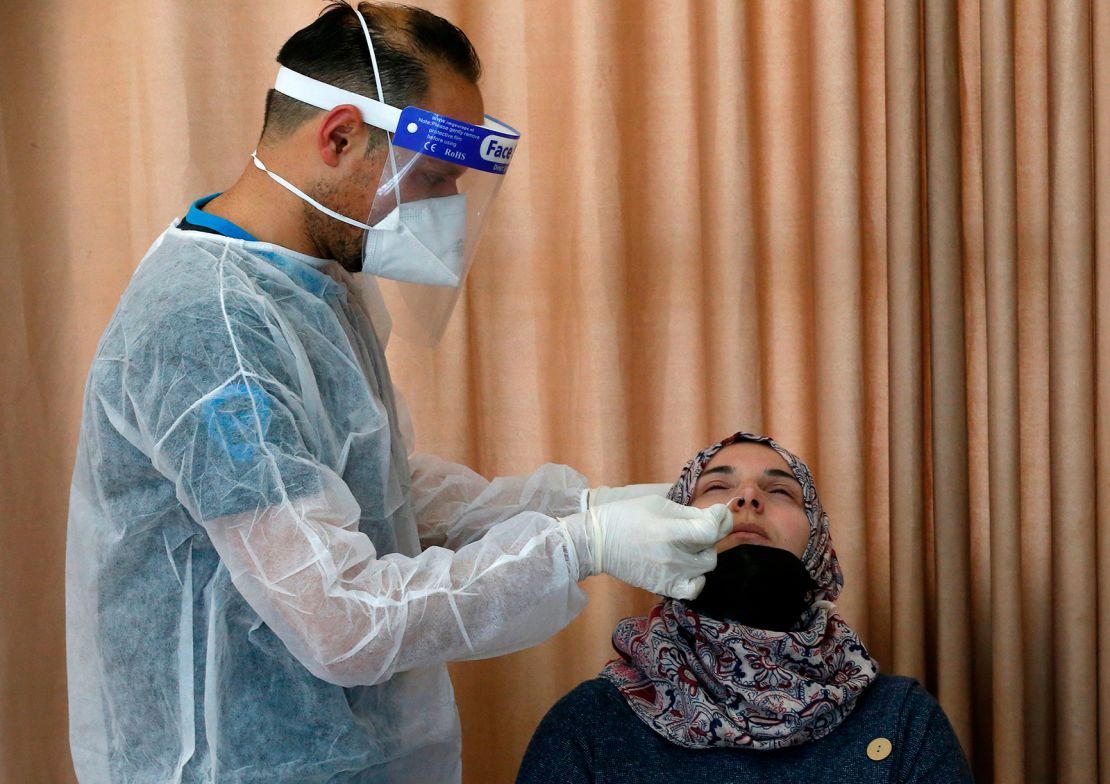 A Palestinian health worker tests a woman for Covid-19 in the West Bank village of Dura, southwest of Hebron, on January 8, 2021.