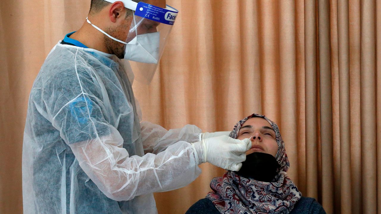 A Palestinian health worker tests a woman for Covid-19 in the West Bank village of Dura, southwest of Hebron, on January 8, 2021.