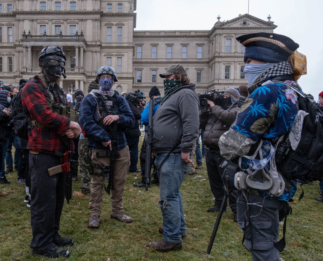 Members of the Michigan Boogaloo Bois, an anti-government group, stand with their long guns on Sunday near the Capitol Building in Lansing, Michigan.