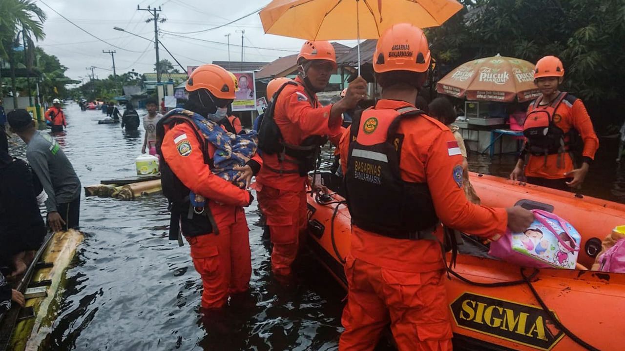 Rescuers evacuate people from a flooded residential area in Banjarbaru, South Kalimantan, Borneo Island, on 17 January 2021.