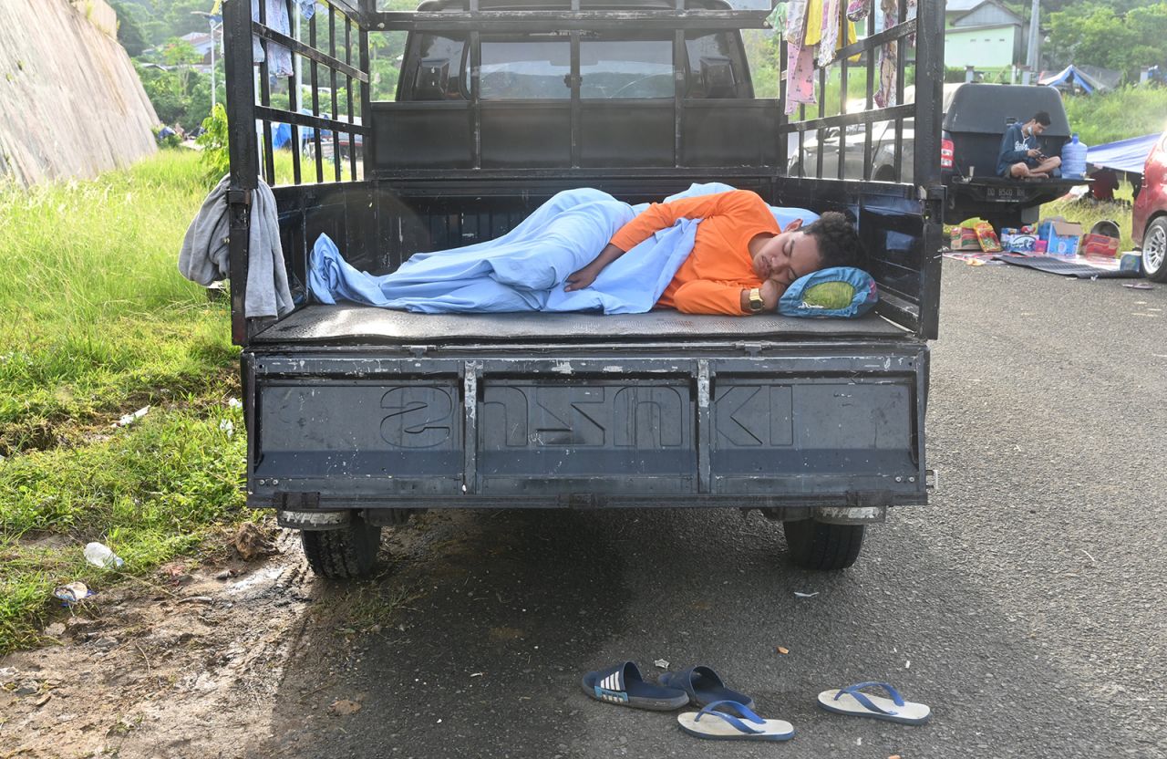 A man sleeps on the back of a truck as people take temporary shelters in Mamuju, on January 18.